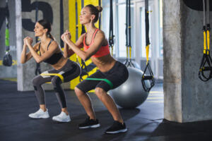 Two women working out with elastic bands in a gym