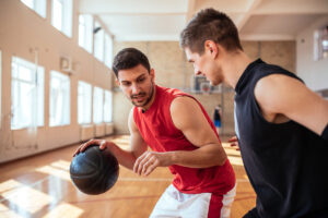 Two young men playing basketball in a gym