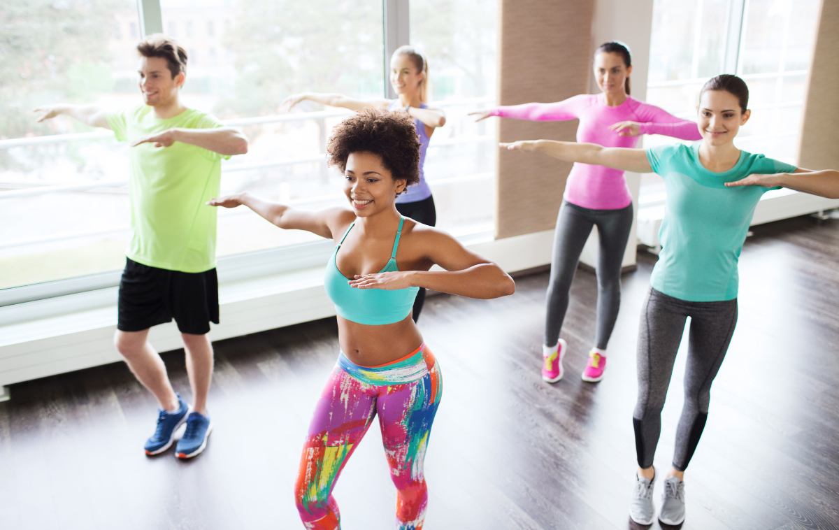 group of smiling people dancing in gym or studio