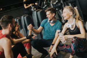 Friends in sportswear talking and laughing together while resting in the gym after a workout