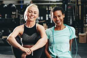 Smiling female friends sittting at the gym after working out